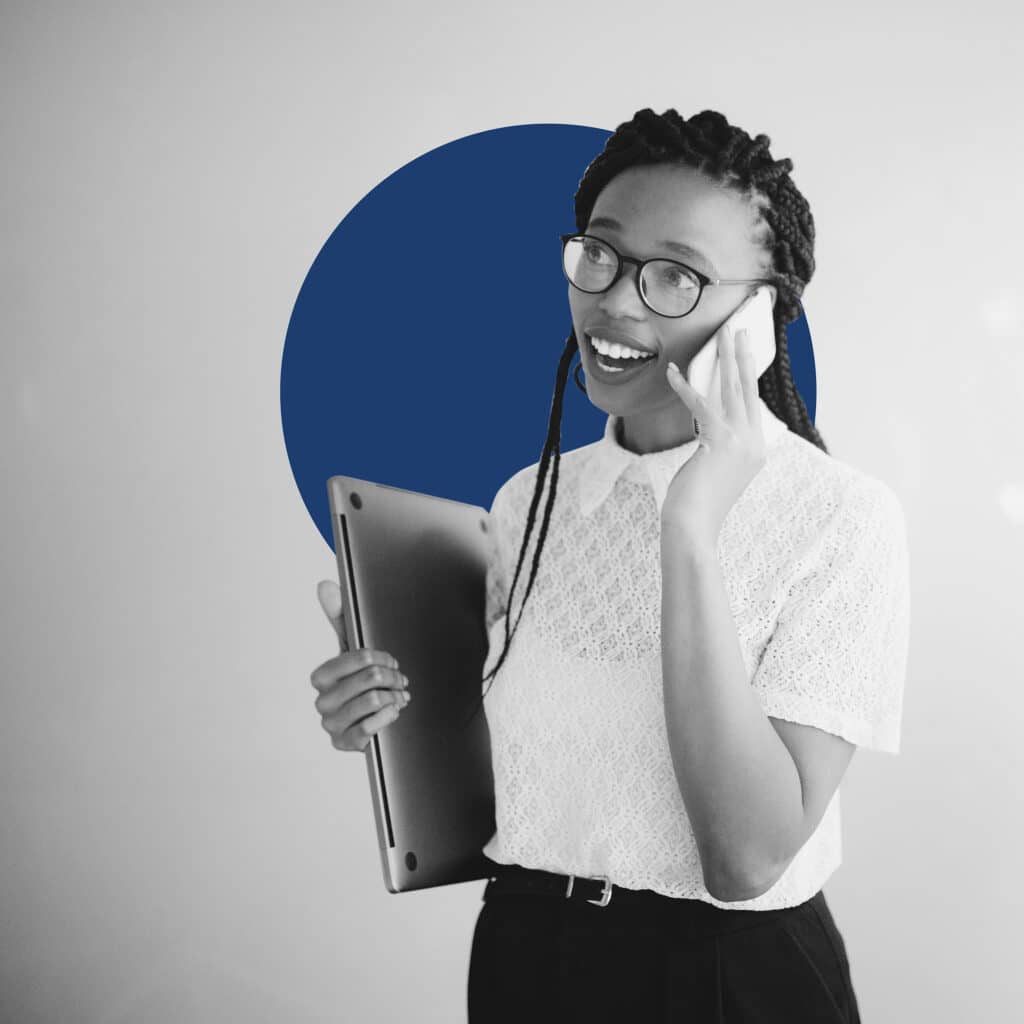 a young black woman talks on the phone with a laptop in hand and a blue branded bubble behind her to illustrate digital advertising terms