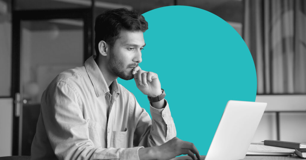 A man in profile works on a laptop with a pensive expression.