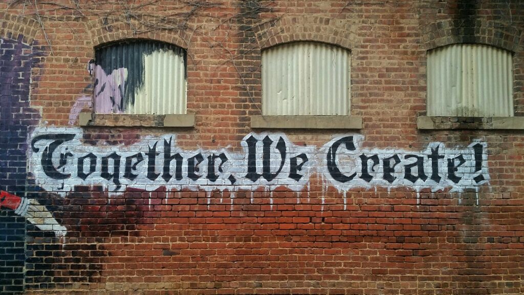 Graffiti on a brick wall reads "Together, we create!" to illustrate the necessity of creative briefs.