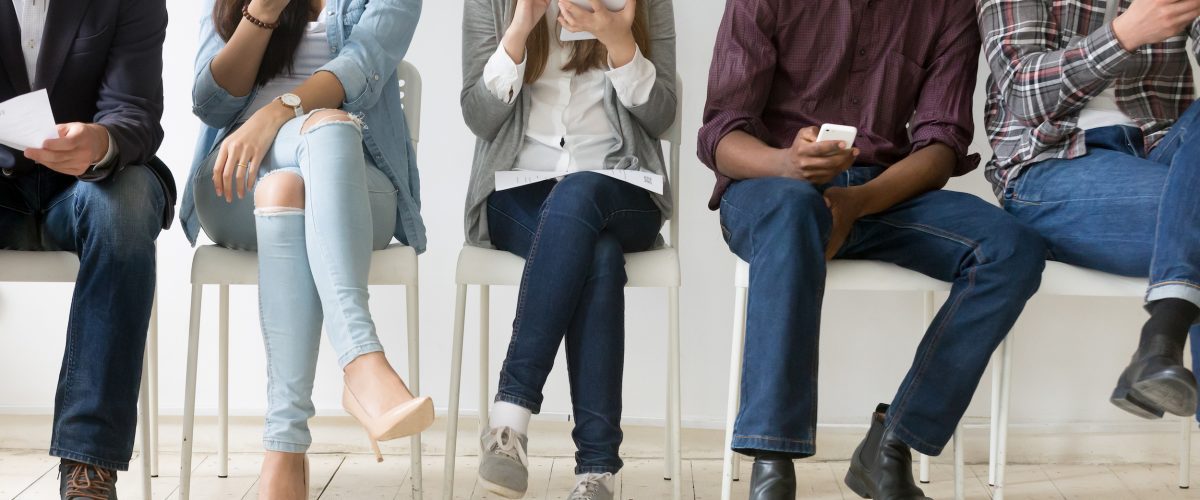 People sitting in a waiting room receiving SMS messages on their mobile devices.