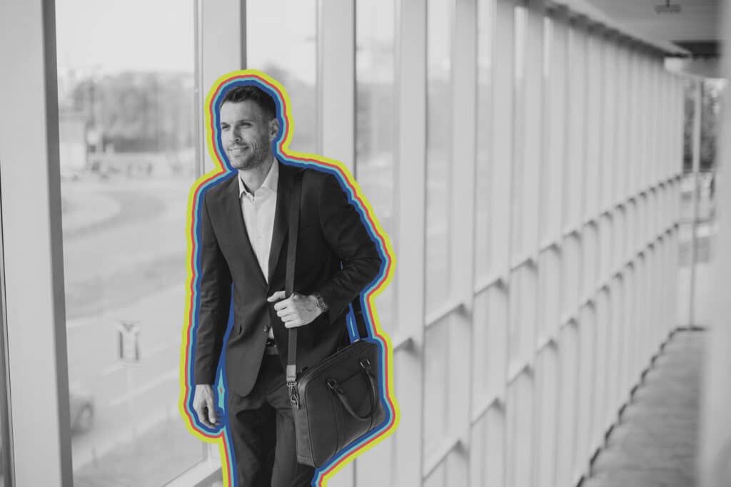 A man walks down a well lit corridor with a briefcase.