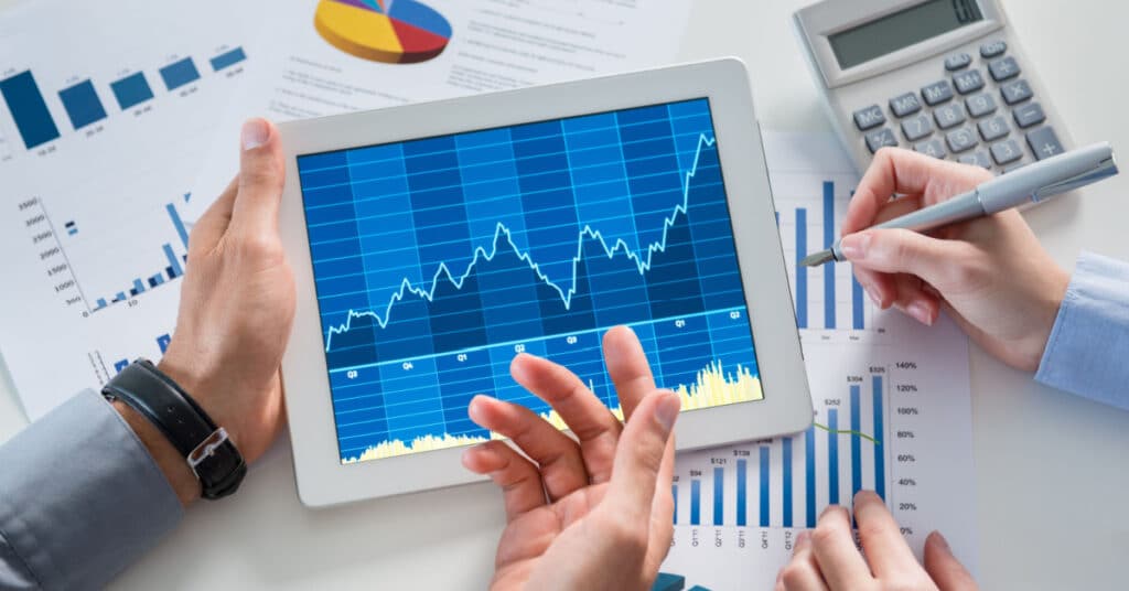 Closeup of an ipad and printed charts showing the performance of an investment portfolio.
