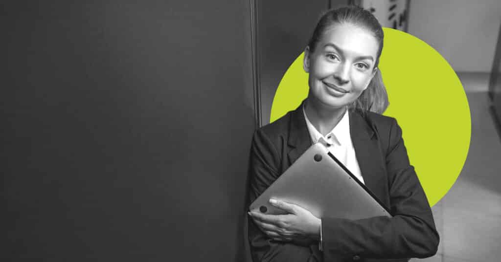 A woman holds a closed laptop and looks at the screen to illustrate the idea of welcome emails