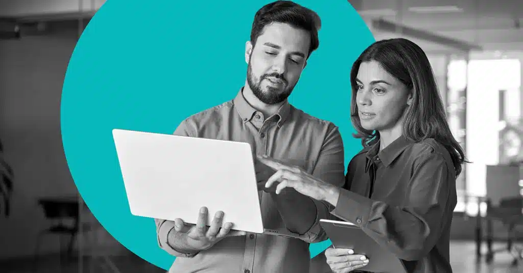 Two professionals hold up a laptop and discuss CCPA compliance.